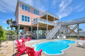 a house with a swimming pool and red chairs at West Point in Oak Island