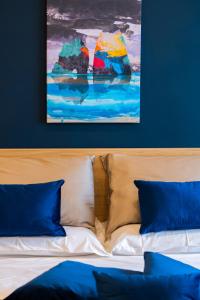 ein Bett mit blauen Kissen und ein Gemälde an der Wand in der Unterkunft La Casa di Leo - Rooms at the feet of Vesuvius in Boscotrecase