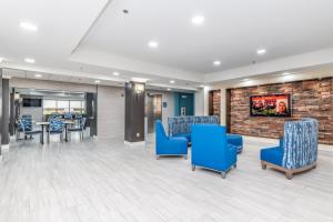 a lobby with blue chairs and a brick wall at Days Inn & Suites by Wyndham Prattville-Montgomery in Prattville