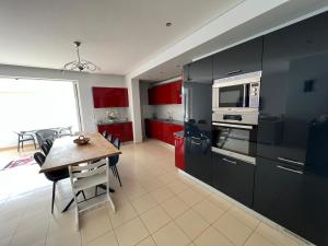 a kitchen with red cabinets and a table and a microwave at Lovely 2 bedroom apartment with a great sea view in Sarandë +22 photos