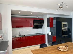 a kitchen with red cabinets and a wooden table at Lovely 2 bedroom apartment with a great sea view in Sarandë