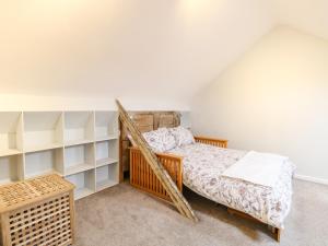 a bedroom with a bed and shelves at Unthank Cottage in Norwich