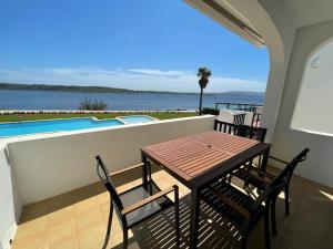 un balcone con tavolo, sedie e piscina di ES CASTELL 1 6 by SOM Menorca a Fornells