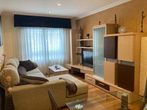 uma sala de estar com um sofá e uma televisão em HyP - El Nido de Iría em Poio