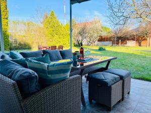 eine Terrasse mit einem Sofa und einem Tisch mit einer Flasche Wein in der Unterkunft Csipkebogyó Nyaralóház - Siófok in Siófok