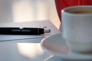 Una taza de café junto a un libro y una taza de café en LÉGÈRE HOTEL Bielefeld, en Bielefeld