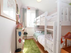 ein Schlafzimmer mit weißen Etagenbetten und einem grünen Teppich in der Unterkunft Sea Mouse Cottage in Southwold