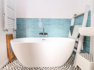 eine Badewanne im Bad mit blauen Fliesen in der Unterkunft Sea Mouse Cottage in Southwold