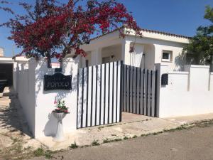 a white house with a fence and a sign at B&B Del Popolo in Torre Chianca