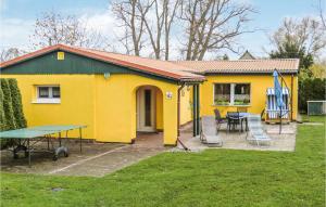 ein gelbes Haus mit einem Tisch und Stühlen im Hof in der Unterkunft Ferienhaus Dubkevitz E in Ummanz