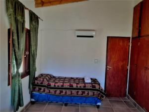 ein kleines Schlafzimmer mit einem Bett und einer Tür in der Unterkunft Casa de CAMPO HUAKA HUASY in Cachí