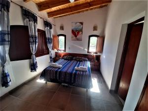 um quarto com uma cama num quarto com janelas em Casa de CAMPO HUAKA HUASY em Cachí