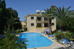 a swimming pool in front of a building with palm trees at Odysseas & Eleni Hotel Apartments in Polis Chrysochous