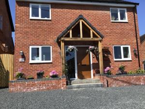 a brick house with a front door with flowers at Luxurious 3 bedroom house Shangri la in village of Alfrick with free off road parking for 3 cars in an area of outstanding natural beauty, superb walking,close to Worcester, Malvern showground, theatre, Malvern hills, dogs welcome in Worcester