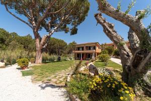 une maison avec un jardin et des arbres devant elle dans l'établissement Villa Cecilia - Appartamenti, à Procchio