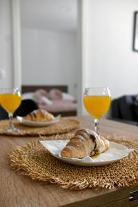 - une table avec deux assiettes de pain et des verres de jus d'orange dans l'établissement Golden Neretva apartments, à Metković
