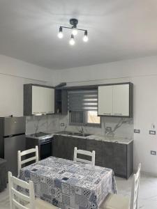 een keuken met een tafel en stoelen en een keuken met witte kasten bij Taku apartment in Sarandë