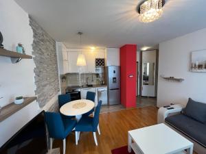 a kitchen and a living room with a table and chairs at Rona Apartments in Novi Sad