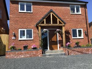 a brick house with flowers on the door at Luxurious 3 bedroom house Shangri la in village of Alfrick with free off road parking for 3 cars in an area of outstanding natural beauty, superb walking,close to Worcester, Malvern showground, theatre, Malvern hills, dogs welcome in Worcester