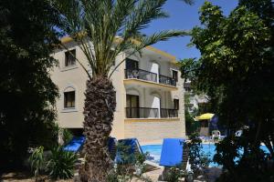 un edificio con una palmera frente a una piscina en Odysseas & Eleni Hotel Apartments, en Polis Chrysochous