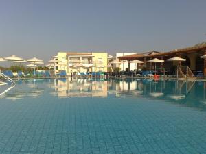 a large swimming pool with chairs and umbrellas at Aktea Beach Village in Ayia Napa