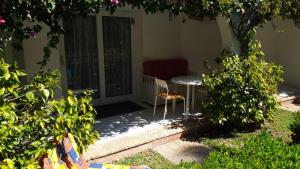 a patio with a table and a chair in a yard at Lujoso apartamento Oasis con piscina a 50 metros de la playa y pueblo de Denia in Denia