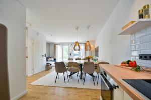 eine Küche mit weißen Wänden und einem Tisch mit Stühlen in der Unterkunft Ferienhaus Olivenoog in Wangerooge