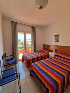 a bedroom with two beds and chairs and a window at G&G Premium Los Alamos in Torremolinos