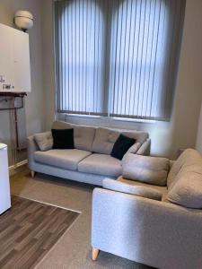 een woonkamer met een bank en een groot raam bij Cosy Convenient 1 BR Flat at Central Stoke Near Hospitals and Univesities in Stoke on Trent