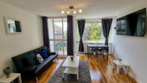 a living room with a black couch and a table at Lovely 2 bed Flat in S/E London in Abbey Wood