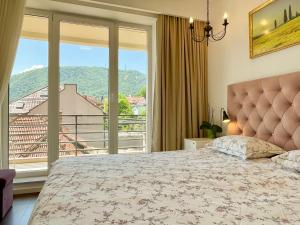 a bedroom with a bed and a large window at Central Premium Apartment in Braşov