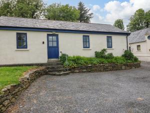 a white house with blue windows and a stone wall at Ballyvoreen in Glandore