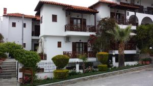 a white house with balconies on a street at Pansion Irini in Ouranoupoli