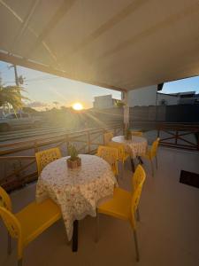 a patio with tables and yellow chairs and the sunset at Pousada Mangaba in Barreirinhas