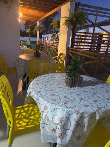 a patio with two tables and yellow chairs and a table with a table cloth at Pousada Mangaba in Barreirinhas
