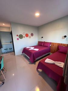 um quarto com 2 camas e lençóis roxos em Pousada Mangaba em Barreirinhas