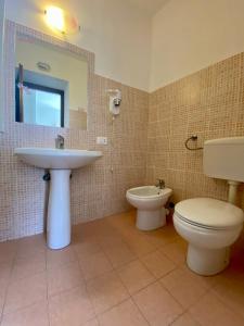 a bathroom with a sink and a toilet and a mirror at Monolocale Nonna Ita in Santa Teresa Gallura