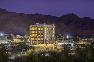 a tall building in front of a city at night at De-Lara hotel in Aqaba