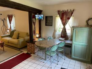 - un salon avec une table, des chaises et un canapé dans l'établissement Le Douet Fleury - Gîte de Jardin, à Livarot