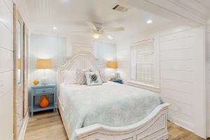 a white bedroom with a bed and a ceiling fan at Jewel's Cottage in Demere Park