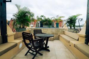 a table and chair on a balcony with palm trees at 7CN-3 CASA DE 7 HABITACIONES EN EL CENTRO HISTORICO in Cartagena de Indias