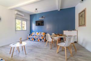 Grand studio climatisé avec piscine - 3 étoiles في Villemoustaussou: غرفة معيشة بجدار ازرق وطاولة وكراسي