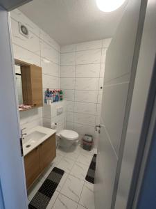 a white bathroom with a toilet and a sink at BesTer Apartment in Ferizaj +11 photos