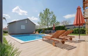 a swimming pool with chairs and an umbrella at 3 Bedroom Amazing Home In Donji Prolozac in Donji Proložac