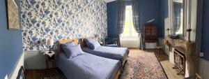 1 dormitorio con paredes azules, 1 cama y chimenea en Château de Mauvilly, en Mauvilly