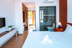um quarto com uma cama branca e uma casa de banho em Ngọc Hoa - Nam Hội An Hotel em Thăng Bình