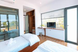a bedroom with a large window and a tv at Ngọc Hoa - Nam Hội An Hotel in Thăng Bình