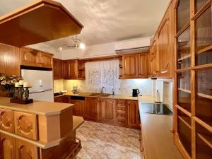 a kitchen with wooden cabinets and white appliances at Seashell Holiday Studios in Ermioni