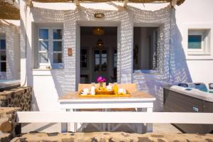 Phaos Santorini Suites في إيميروفيغلي: طاولة بيضاء على الشرفة الأمامية للمنزل