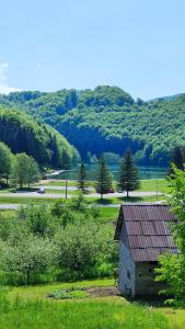 eine Scheune auf einem Feld mit See und Bergen in der Unterkunft Apartmani Toki Balkana in Mrkonjić Grad